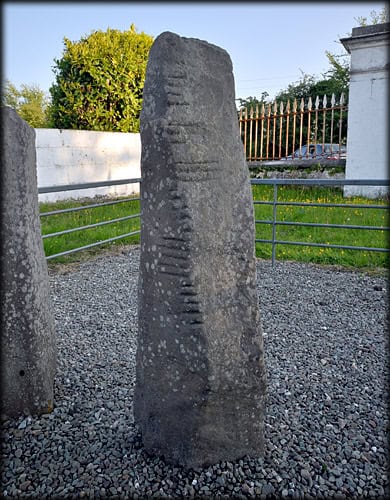 A tall, weathered ogham stone with carved runes.