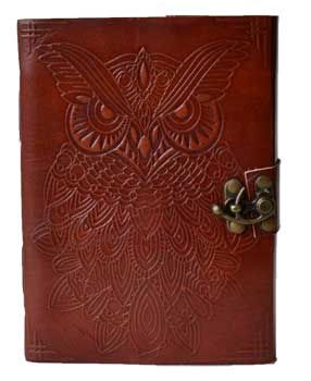 Leather-bound book with owl and ogham carvings, metal clasp, on a wooden surface.