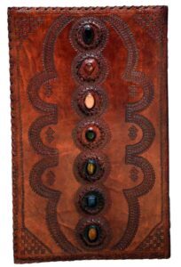 Ancient leather ogham tablet featuring carved symbols and embedded colored stones, used in Celtic sp.