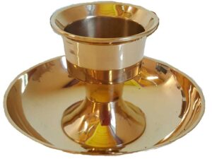 A shiny gold cup with a broad, flat dish underneath, used in spiritual or ritual practices.
