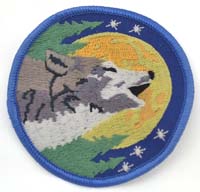 Patch featuring a wolf howling at a yellow moon with stars, set against a blue background.