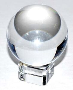 A glass crystal ball resting on a transparent stand, reflecting light and creating a smooth, rounded.