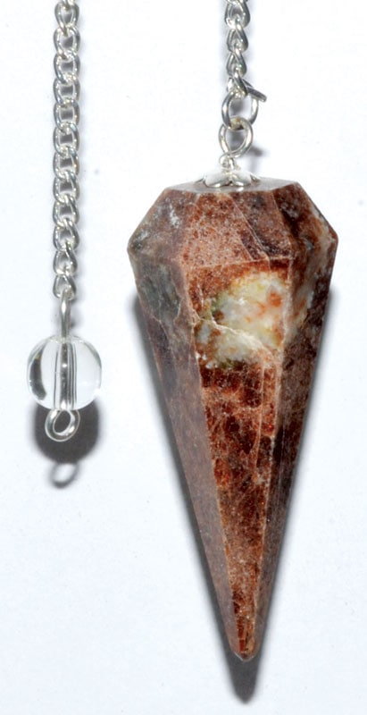 Stone pendant with a pointed, faceted shape and natural earthy tones, attached to a silver chain.