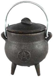Cauldron with pentagram symbol, made of dark metal, with a handle and three legs.