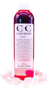 Bottle of Love Moon water with pink rose petals around it, on a white background.