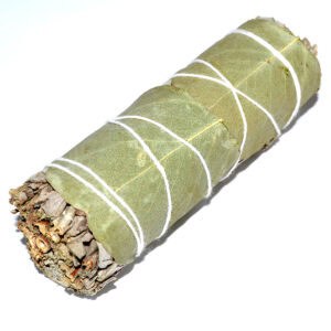 Bundle of small wooden sticks tied with white string, wrapped in green leaves.