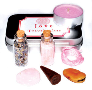 A travel altar setup featuring a pink candle, herbal bottles, and stones for Celtic spiritual ritual.