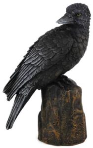 A detailed sculpture of a black crow perched on a textured wooden base.