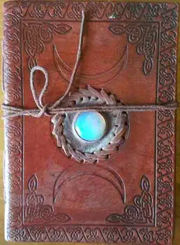 Leather journal with ogham pendant and cord, featuring Celtic knotwork and symbols.