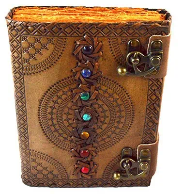Leather-bound Celtic ogham book with metal clasps and colorful gemstone decorations.