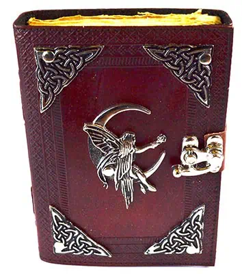 Close-up of a Celtic-style book with silver corner decorations and a fairy charm on the cover.