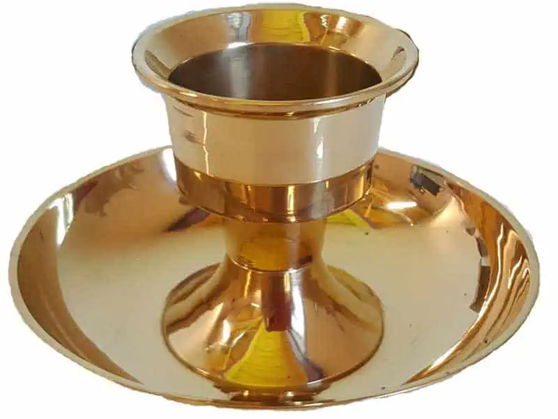 A shiny gold cup with a broad, flat dish underneath, used in spiritual or ritual practices.