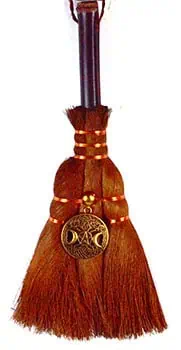 A traditional wooden brush with a leather strap and brass ornament.