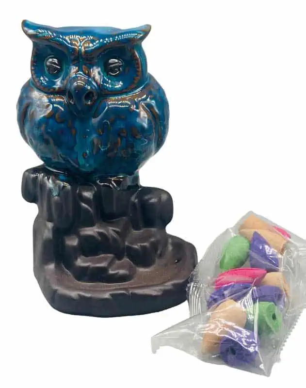 A blue ceramic owl candle holder with intricate details, placed on a dark base.