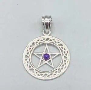 A silver pendant with a pentagram and purple gemstone, set within a detailed circular frame, reflect.
