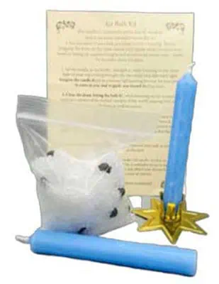 A Celtic-themed Yule decoration featuring candles, a scroll, and a small bag of herbs or potpourri.