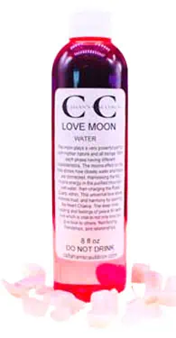 Bottle of Love Moon water with pink rose petals around it, on a white background.
