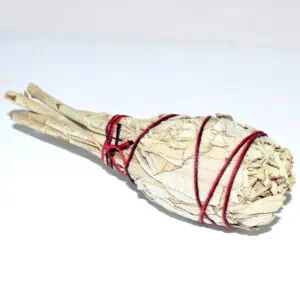 A bundle of dried herbs and twigs tied with red string, used in spiritual practices.