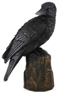 A detailed sculpture of a black crow perched on a textured wooden base.